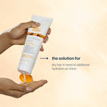 Load image into Gallery viewer, Hand holding a tube of milk_shake moisture plus conditioner with text on a beige background