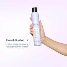 Load image into Gallery viewer, Hand holding a bottle of milk_shake strong eco hairspray with text on a light purple background