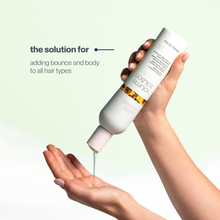 Load image into Gallery viewer, Hand holding a bottle of milk_shake volume shampoo with text on a light green background