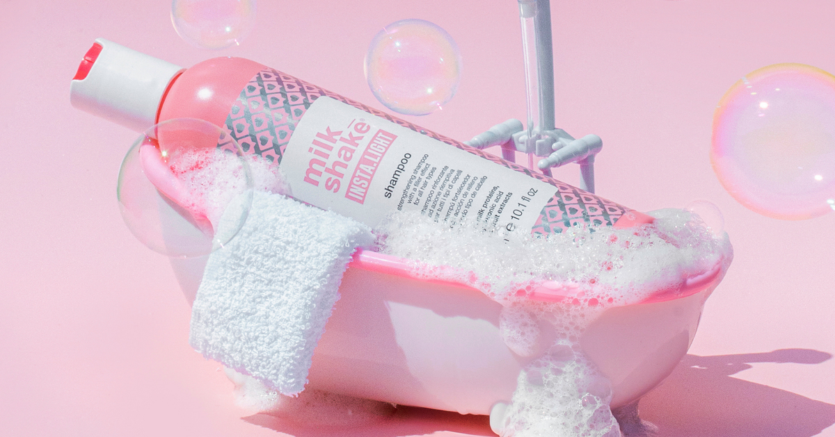 bottle of milk_shake INSTA.LIGHT shampoo in a bath surrounded by pink and bubbles 