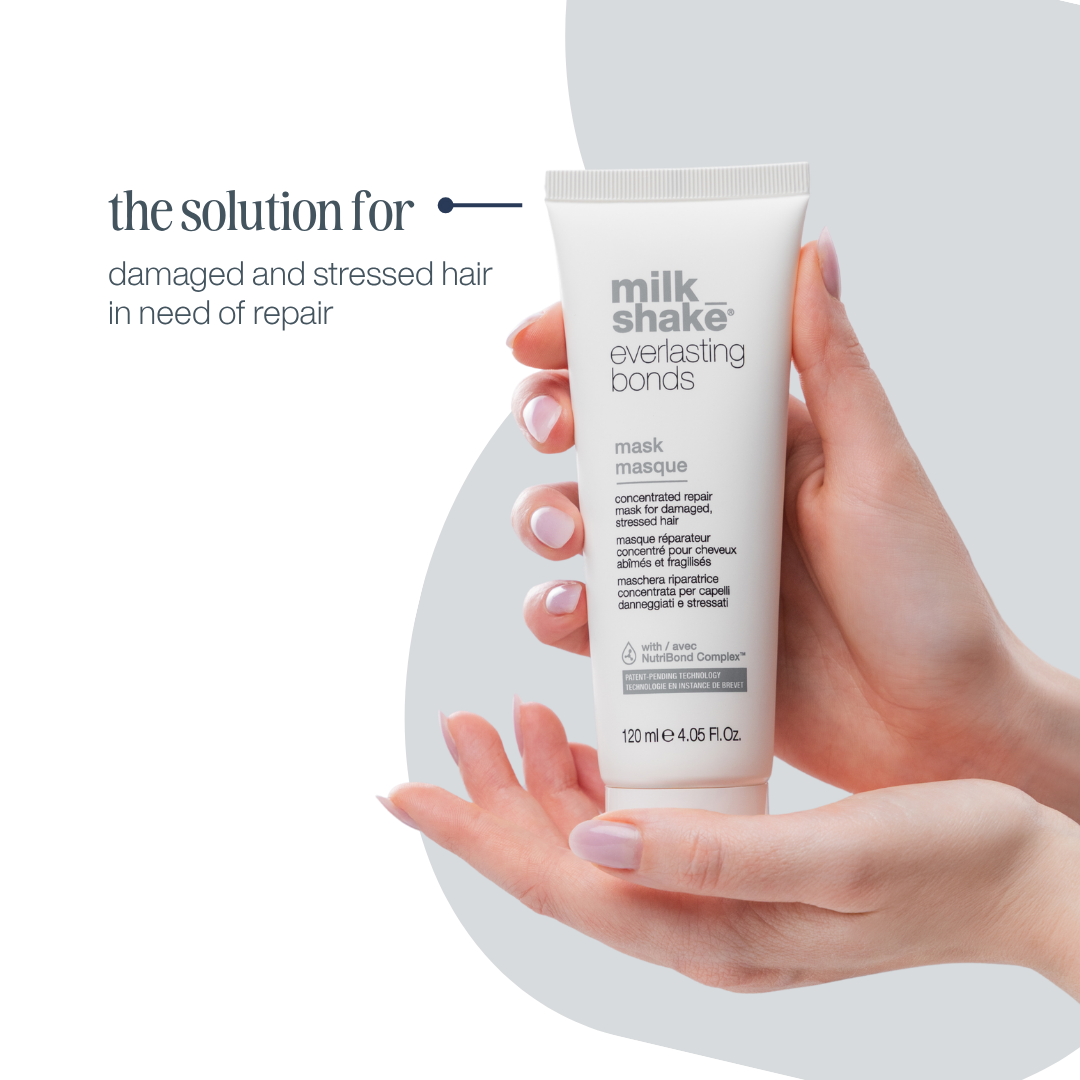 Hand holding a tube of Milk Shake Everlasting Bonds mask against a light background