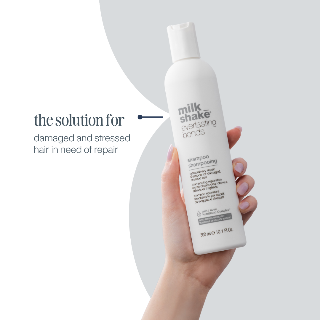 Hand holding a bottle of 'milk_shake' shampoo with text on a light gray background
