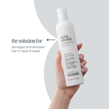 Load image into Gallery viewer, Hand holding a bottle of 'milk_shake' shampoo with text on a light gray background
